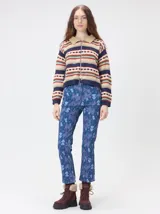 Campera de punto con cierre frontal metálico y cuello de corderito. Presenta un diseño estampado con franjas horizontales en tonos azul marino, beige, rojo y verde.