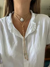 Collar de cuero azul con dije plateado en forma de caracol y detalles de cuentas plateadas. El collar tiene dos tiras que caen por el frente.