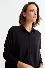 Cardigan de punto color crema, con cuello camisero, cierre frontal de botones y bolsillo frontal en el pecho.