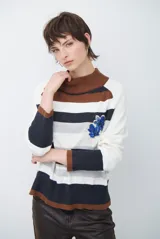 Polera de tejido de punto con diseño de rayas horizontales en tonos beige, marrón, gris y negro. Presenta cuello redondo y mangas largas con puños en contraste.