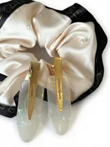 Kit de accesorios para el cabello que incluye un neceser transparente con borde blanco, dos scrunchies (uno negro con perlas y uno beige), dos clips livianos, una pinza dorada, un peine protector para desenredar y un peine para abrir ondas y rulos.