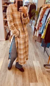 Tapado largo de paño extra liviano con estampado a cuadros en tonos beige y marrón. Presenta cuello redondo, cierre frontal, bolsillos laterales y tajos profundos en los costados.