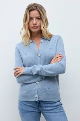 Cardigan de punto color ocre, con diseño calado de pequeños motivos florales, cuello polo y cierre frontal con botones.