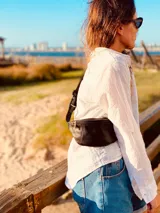 Riñonera de cuero color marrón claro con cierre superior y correa ajustable.