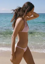 Top de bikini triangular color rosa con detalle de eyelets metálicos en los breteles. Se ata en la espalda con lazos y tiene relleno.