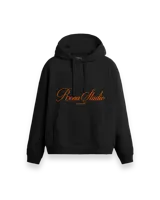 Hoodie negro oversize con diseño bordado en el frente con la inscripción "Roona Studio" en color naranja.