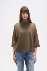 Polera de corte holgado en color verde oliva, con cuello alto y mangas tres cuartos.