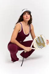 Conjunto deportivo compuesto por un top y un pantalón largo en color bordó. El top presenta un diseño con cuello redondo y ribetes blancos, con el logo 'bk.' estampado en el frente. El pantalón es de corte ajustado con cintura cruzada en V y detalle de ribete blanco, con terminación acampanada en los tobillos.
