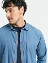 Camisa de denim de algodón con cuello clásico, cierre frontal con botones, bolsillo superior de parche y mangas largas con puños abotonados.