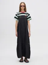 Vestido midi de denim color marrón, con corte holgado, breteles finos con lazos ajustables y detalle de volado en el ruedo.