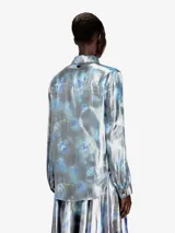 Camisa Diesel C-Ronor-S2 de mujer, manga larga, confeccionada en tejido fluido y semitransparente con acabado metalizado y estampado abstracto de efecto acuarela en tonos azules, plateados y blancos. Presenta cuello clásico y cierre frontal de botones.