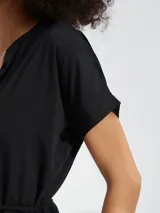 Vestido corto con estampado animal print tipo cebra en tonos blanco y negro. Presenta escote en V, mangas cortas y un lazo ajustable en la cintura para entallar la silueta.