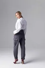 Pantalón gris de tiro alto con pinzas, bolsillos cargo laterales y ruedo ajustable con botones.