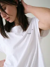Camisón blanco de algodón, de corte holgado, manga corta y largo por encima de las rodillas. Presenta una pequeña estampa localizada en el pecho y aberturas en los laterales.
