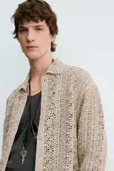 Sobrecamisa de hombre color beige, confeccionada en tejido de crochet con estructura abierta, cuello solapa, manga larga y cierre frontal de botones.