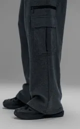 Pantalón tipo jogger gris melange de corte baggy y silueta amplia, confeccionado en frisa de algodón. Presenta cintura elástica, bolsillos laterales de mano y bolsillos estilo cargo con solapa y cierre en los laterales.