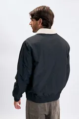 Campera tipo bomber color negro con cuello de corderito en color crema, cierre frontal y puños elásticos.