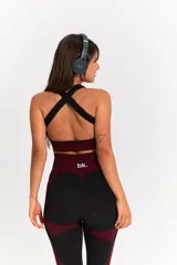 Conjunto deportivo de tres piezas compuesto por un top, una calza chupín de tiro alto y una campera corta con cierre frontal. El diseño presenta una combinación de texturas en color negro y detalles en bordó.
