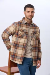 Campera estilo leñadora de viyela a cuadros en tonos beige, marrón y azul, con interior forrado en corderito, cierre frontal con botones y dos bolsillos con solapa en el pecho.