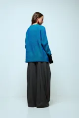 Sweater de punto con hilo de lurex brillante, color azul con rayas verticales en verde. Presenta cuello redondo, mangas largas con puños de piel sintética negra y corte holgado.