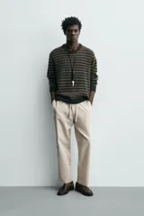 Pantalón de corte relajado confeccionado en una mezcla de algodón y lino. Presenta cintura elástica con cordón ajustable, bolsillos laterales y bolsillos traseros de vivo.