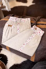 Bombacha de campo color beige, con detalles de tela estampada floreada en la cintura, bolsillos y botamangas. Cuenta con cintura elastizada y cierre con botón.