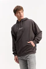 Canguro de algodón con efecto lavado de corte oversize, capucha con cordones ajustables, bolsillo canguro delantero y estampa frontal con texto en el pecho.