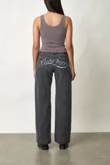 Jean de corte wide leg y tiro medio, color gris oscuro, con diseño de cinco bolsillos y cierre frontal con botón y cremallera.