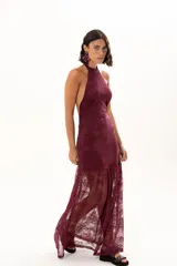 Vestido largo de encaje color bordó, con escote halter y diseño ajustado en el torso que se extiende hasta la cintura, donde continúa con una falda larga de encaje transparente.