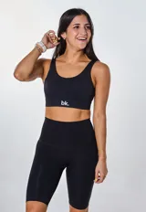 Conjunto deportivo compuesto por un top de escote redondo con logo estampado y un short ciclista de tiro alto, ambos en color negro.