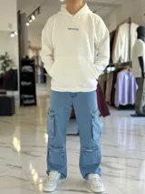 Canguro oversize blanco con capucha y bolsillo tipo canguro, confeccionado con tela de felpa suave. Presenta estampado azul en la espalda con la inscripción "WAIT FOR NOBODY", un diseño de planeta con el año 2021, el logo "STWD" y las frases "CHASE YOUR DREAMS, DON'T SLOW DOWN" y "TOP STYLE".