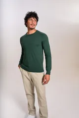 Sweater de punto fino color verde oscuro, con cuello redondo y mangas largas con puños acanalados. Presenta un pequeño logo bordado en el pecho.