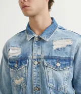 Campera de jean azul claro con efecto delavé, roturas, desgastes y bolsillos frontales con solapa.