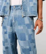 Pantalón de jean de algodón con diseño jacquard geométrico, de corte super baggy, tiro medio, bolsillos funcionales y cierre frontal con botón y cremallera.