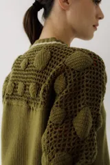 Saco de punto color beige, con diseño de calados en la parte superior y mangas, cierre frontal con botones y cuello redondo.