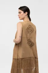 Chaleco de efecto gamuzado color beige, con detalles tejidos al crochet en forma de rombos, flecos largos en el ruedo y diseño sin mangas.