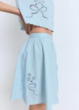 Falda corta evasé de algodón color celeste, con diseño fluido, detalles bordados y bajo festoneado. Cuenta con cierre de cremallera lateral.
