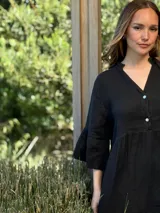 Vestido corto de lino color beige claro, con cuello mao, escote con botones de nácar, mangas tres cuartos con volados y ruedo con volado.