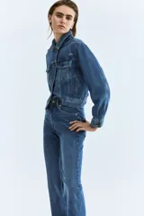 Jean de cinco bolsillos en denim de algodón con stretch. Modelo bootcut de tiro alto, ajustado de cintura a cadera y con corte ligeramente acampanado desde la rodilla hacia el bajo. Presenta raya marcada en la parte delantera y trasera.