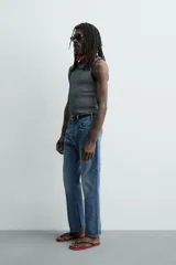 Camiseta sin mangas de corte regular, confeccionada en tejido de algodón con elasticidad. Presenta un diseño de rayas horizontales finas, cuello redondo y acabados en vivo doble.