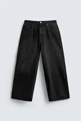 Jeans de denim de algodón, color negro lavado, con corte amplio y holgado (baggy fit) en toda la pierna y tiro medio. Presenta cinco bolsillos y cierre frontal con cremallera y botón.
