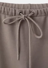 Pantalón de corte ancho, estilo relaxed, color gris topo, con cintura elástica ajustable mediante cordón.