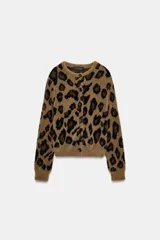 Chaqueta de punto con textura suave, cuello redondo y manga larga. Presenta un diseño de estampado animal print en tonos marrones y negros, con cierre frontal de botones.