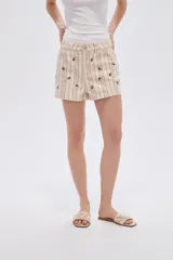 Short de algodón beige con diseño a rayas verticales y pequeño estampado de flores, con bolsillos laterales y cierre frontal con botón y cremallera.