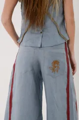 Pantalón de lino color celeste grisáceo, de corte ancho y talle medio, con detalles en bordó y costuras pespunteadas.