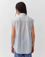 Camisa celeste sin mangas con diseño a rayas sutiles, de corte amplio y silueta fluida. Presenta cuello camisero y cierre frontal parcial con botones.