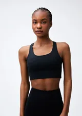 Top deportivo de color negro con diseño de espalda nadadora, confeccionado en tejido elástico y transpirable.