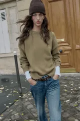 Jersey de punto de cuello redondo y manga larga, con diseño de corte recto y acabados en rib. Presenta detalles de calados decorativos en los laterales.