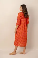Vestido largo de corte holgado en tonos naranja y fucsia con estampado de cuadros vichy. Presenta cuello en V con detalles bordados, mangas tres cuartos y bordados decorativos de palmeras en contraste en las mangas.