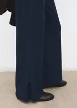 Pantalón azul marino de tiro medio, corte ancho y recto, con pequeñas aberturas en los bajos.